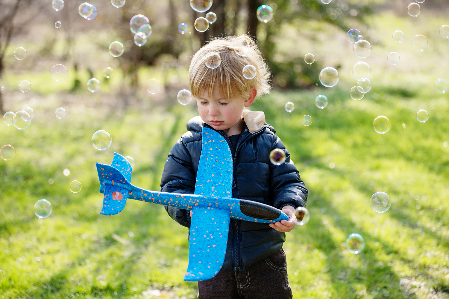 ZACHARY HOLDING AIRPLANE SURROUNDED BY BUBBLES